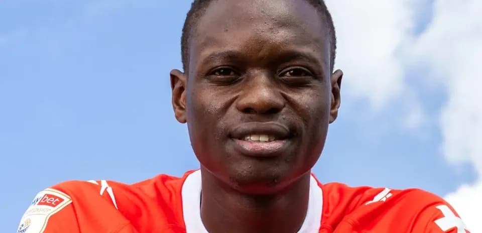 Player in red jersey smiling against blue sky