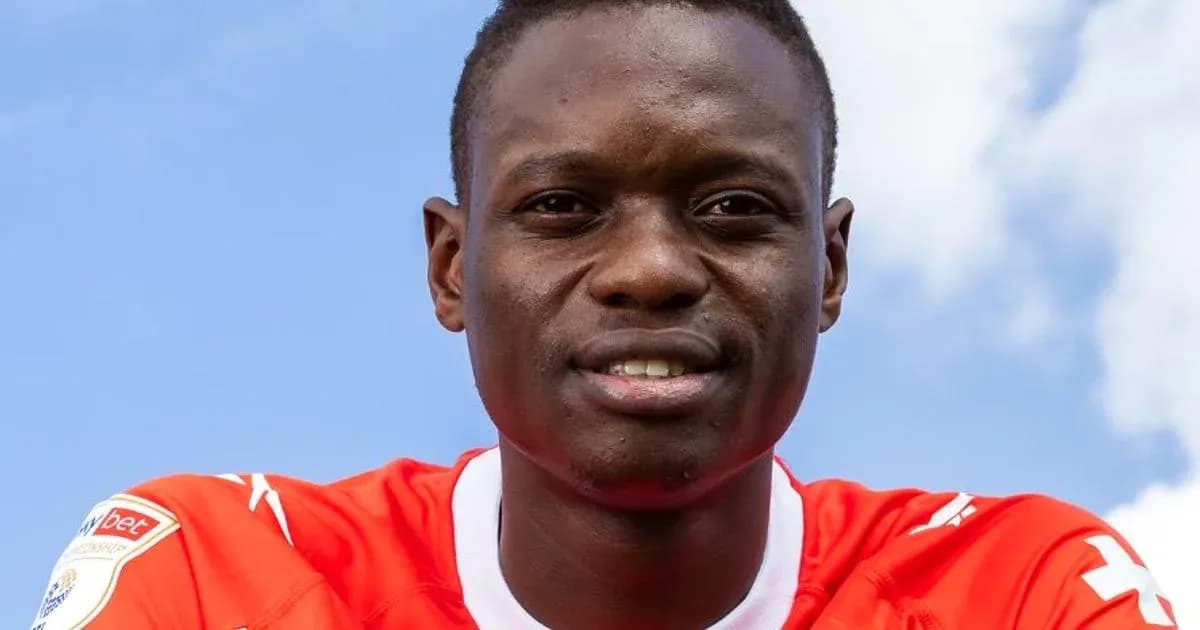 Player in red jersey smiling against blue sky