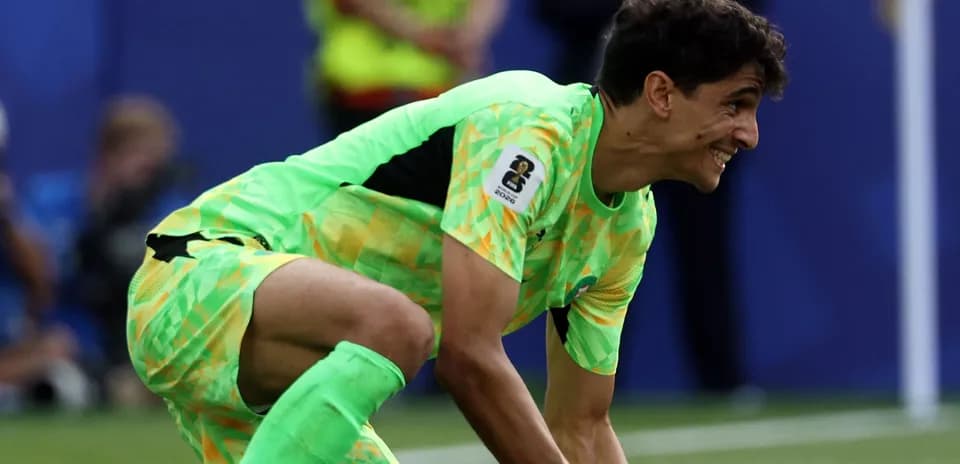 Goalkeeper in green kit preparing to make a save