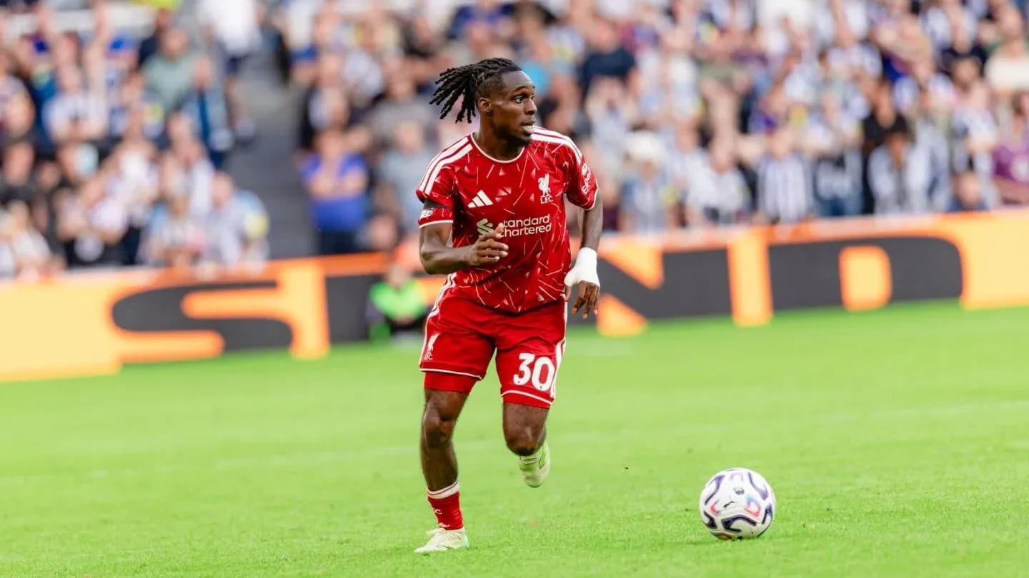 Player in red kit running with ball on field