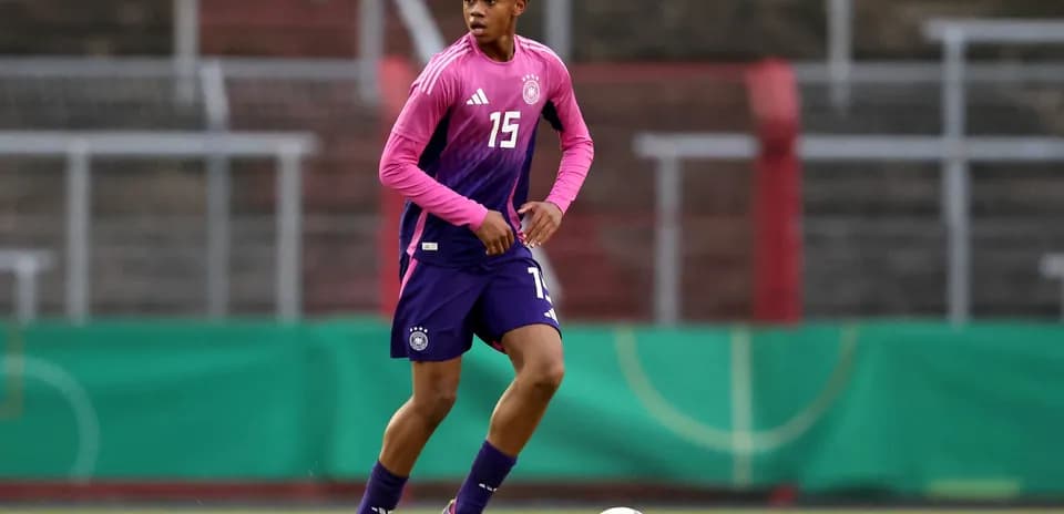 Player in pink and blue uniform dribbling soccer ball