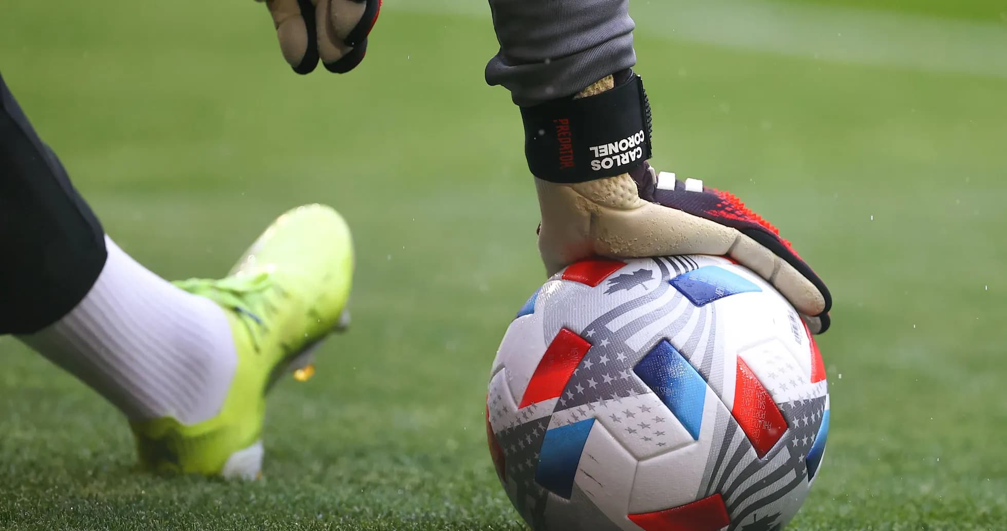 Goalkeeper placing hand on soccer ball on field