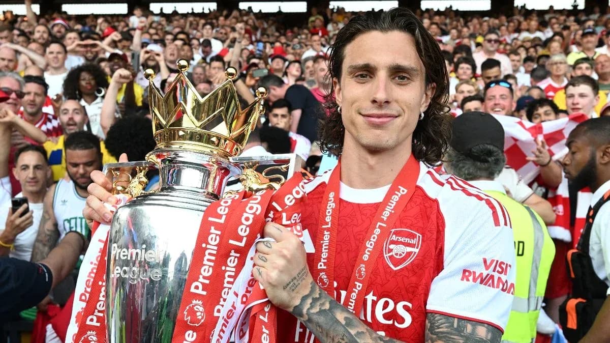 Player holding Premier League trophy surrounded by fans