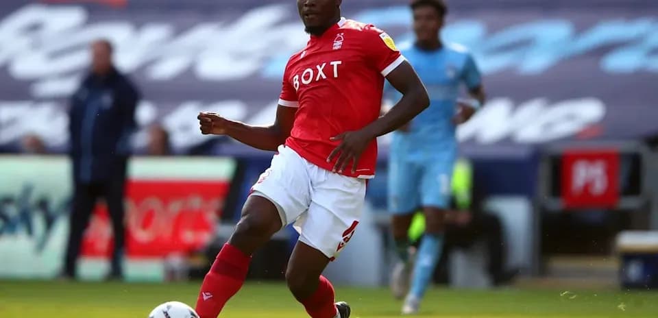 Player in red kit dribbling the ball on pitch