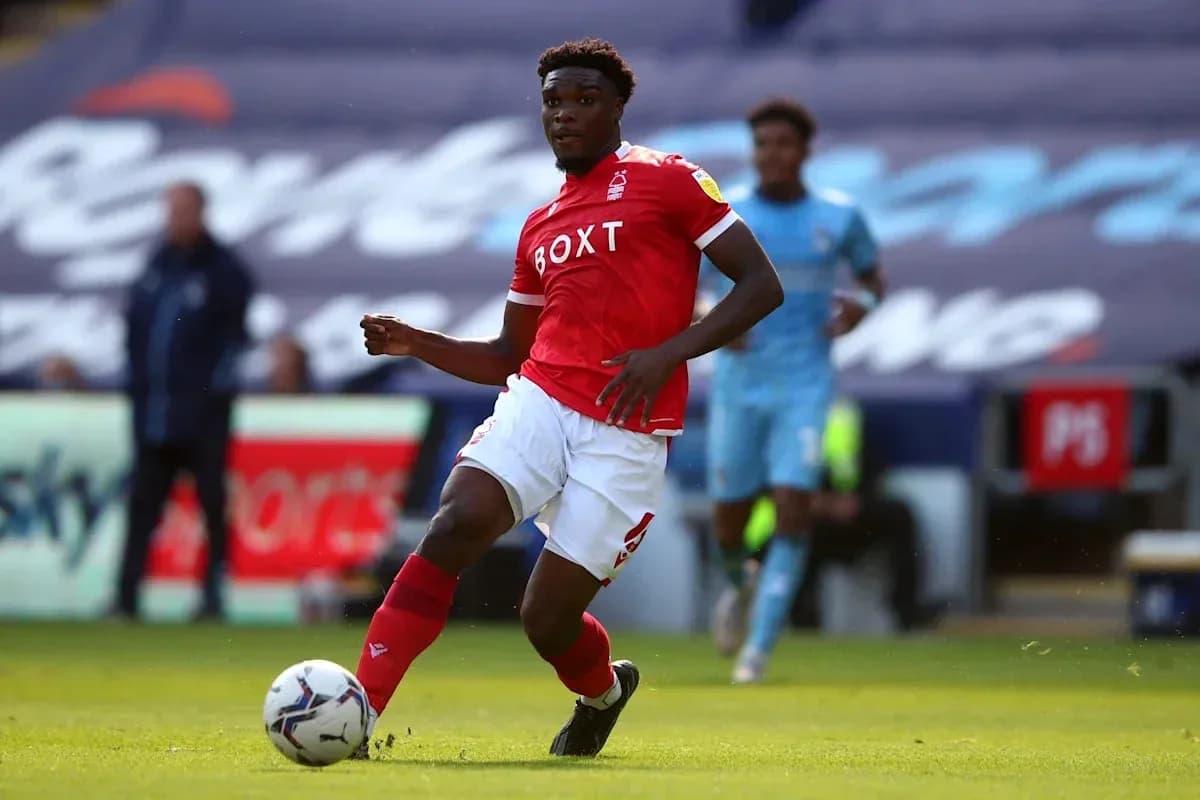 Player in red kit dribbling the ball on pitch