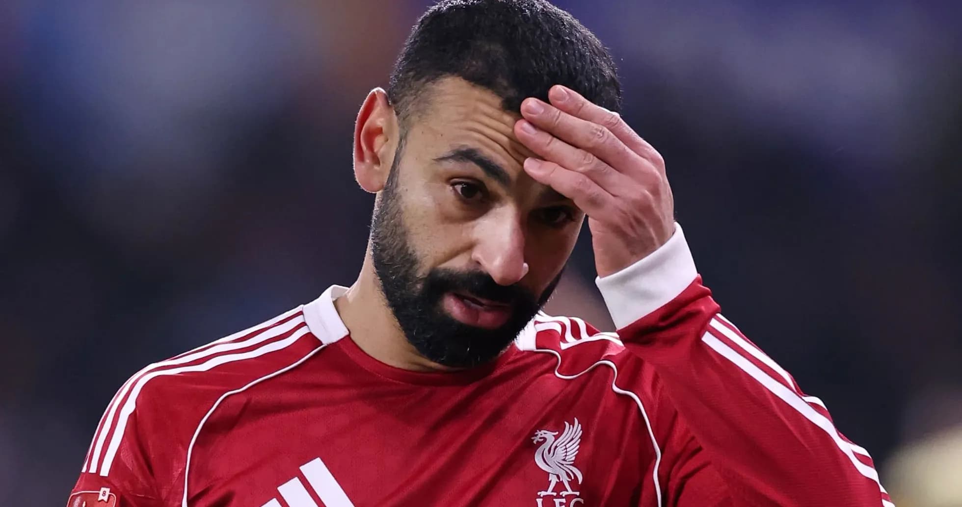 Player in red jersey touching forehead during match