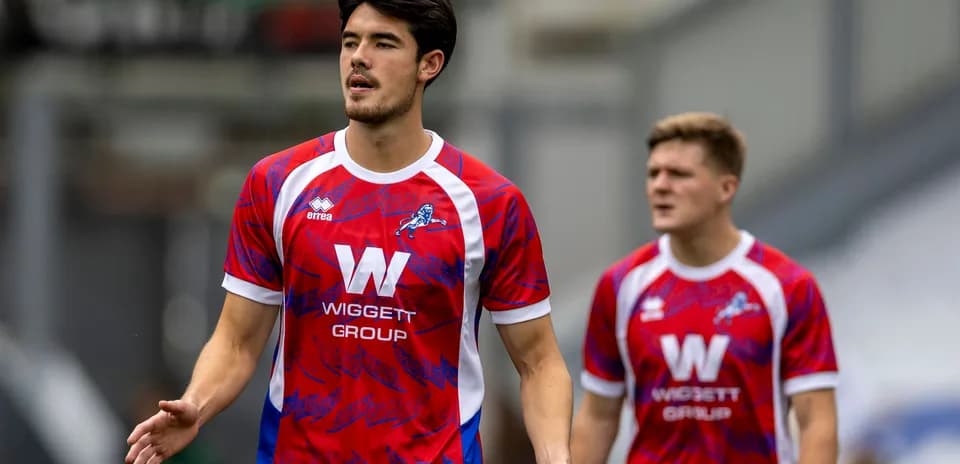 Two players in red and blue team jerseys walking