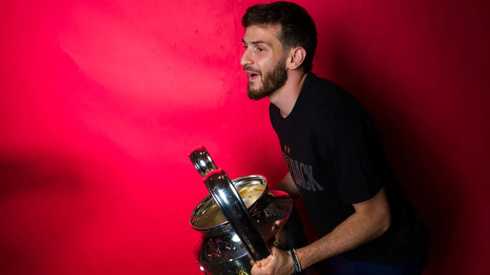 Player holding a trophy against a red background