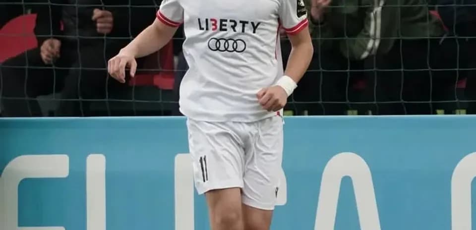 Player in white kit dribbling ball on pitch