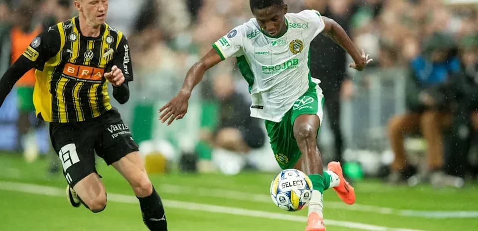 Player in green dribbling past opponent in black jersey