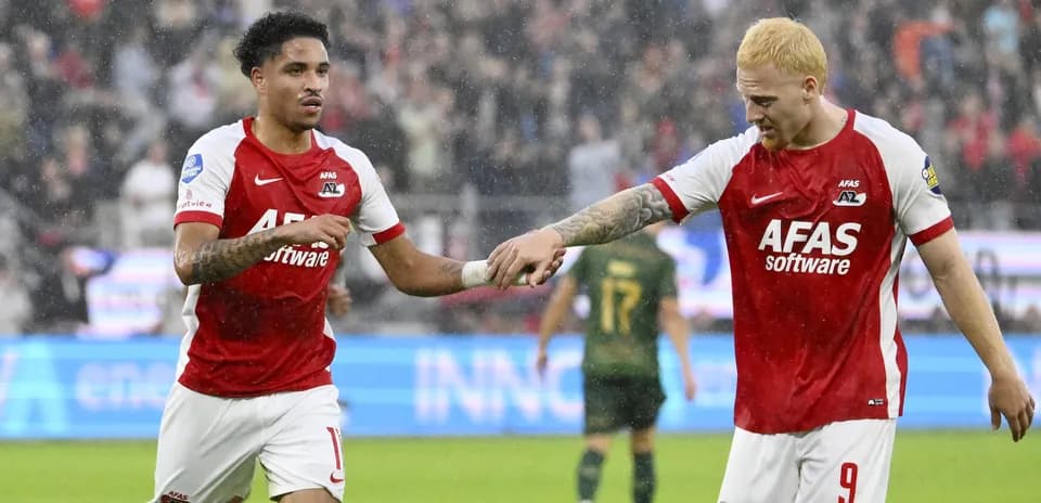Two AZ Alkmaar players celebrating a goal in rain