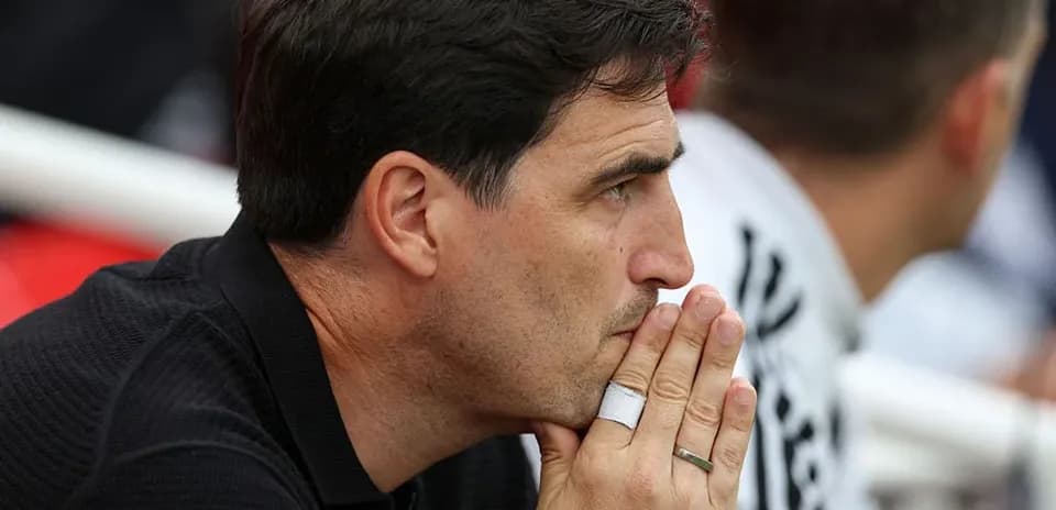 Coach watching match with hands clasped in thought