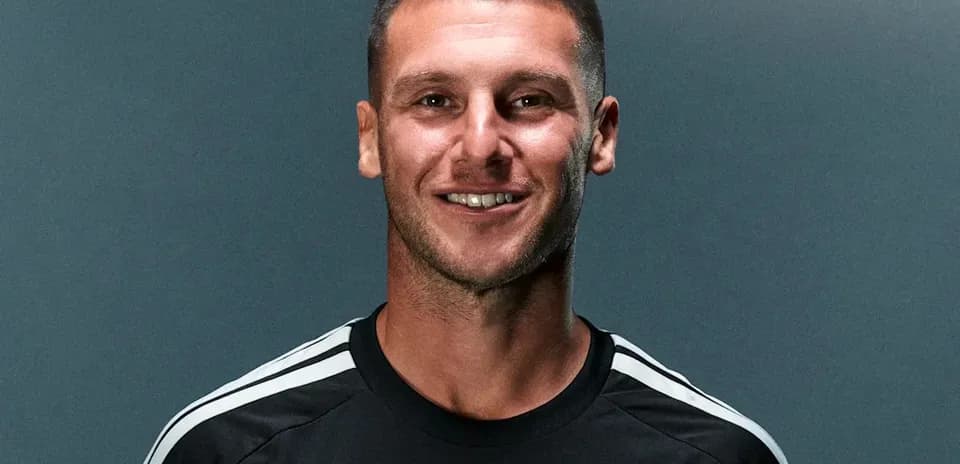Player posing in black jersey with logo