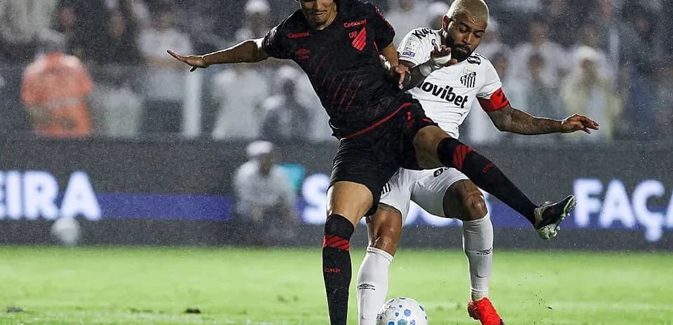 Two players contesting the ball in a rainy match