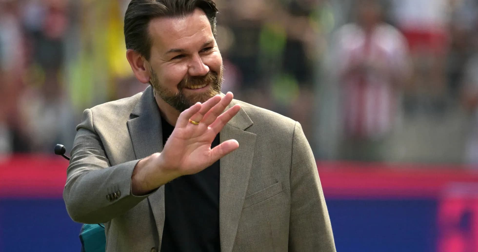 Man in suit waving during a sports event