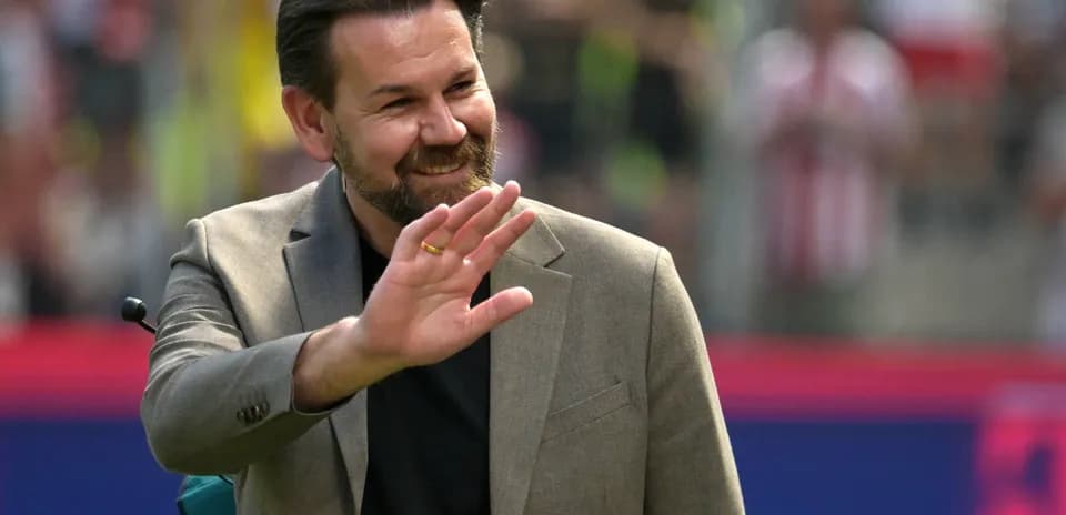 Man in suit waving during a sports event
