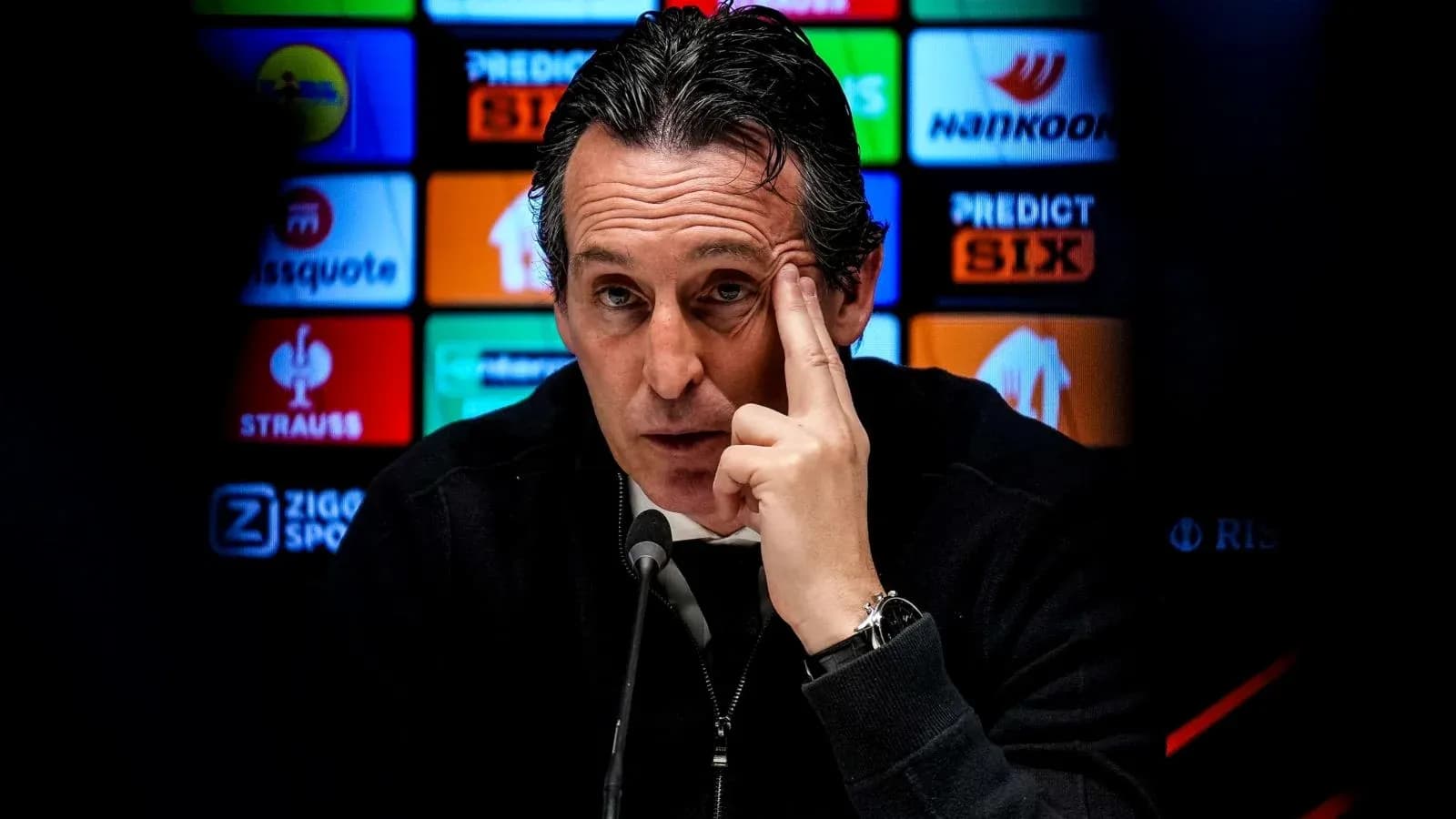 Manager speaking at press conference with sponsors backdrop