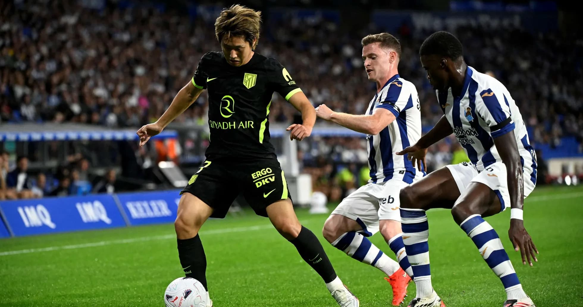 Atletico Madrid player dribbling past Real Sociedad defenders