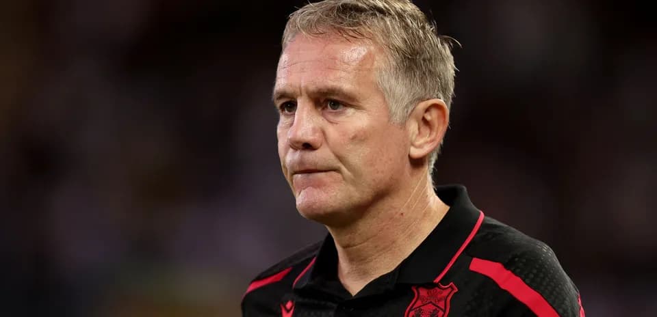 Coach in black and red shirt during match