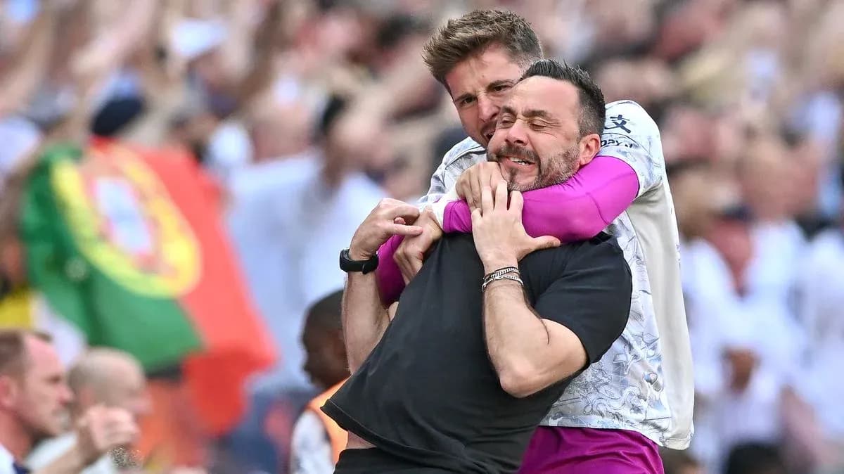Two coaches celebrating a goal on the sidelines