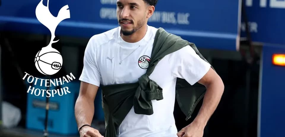 Player walking with jacket draped during arrival