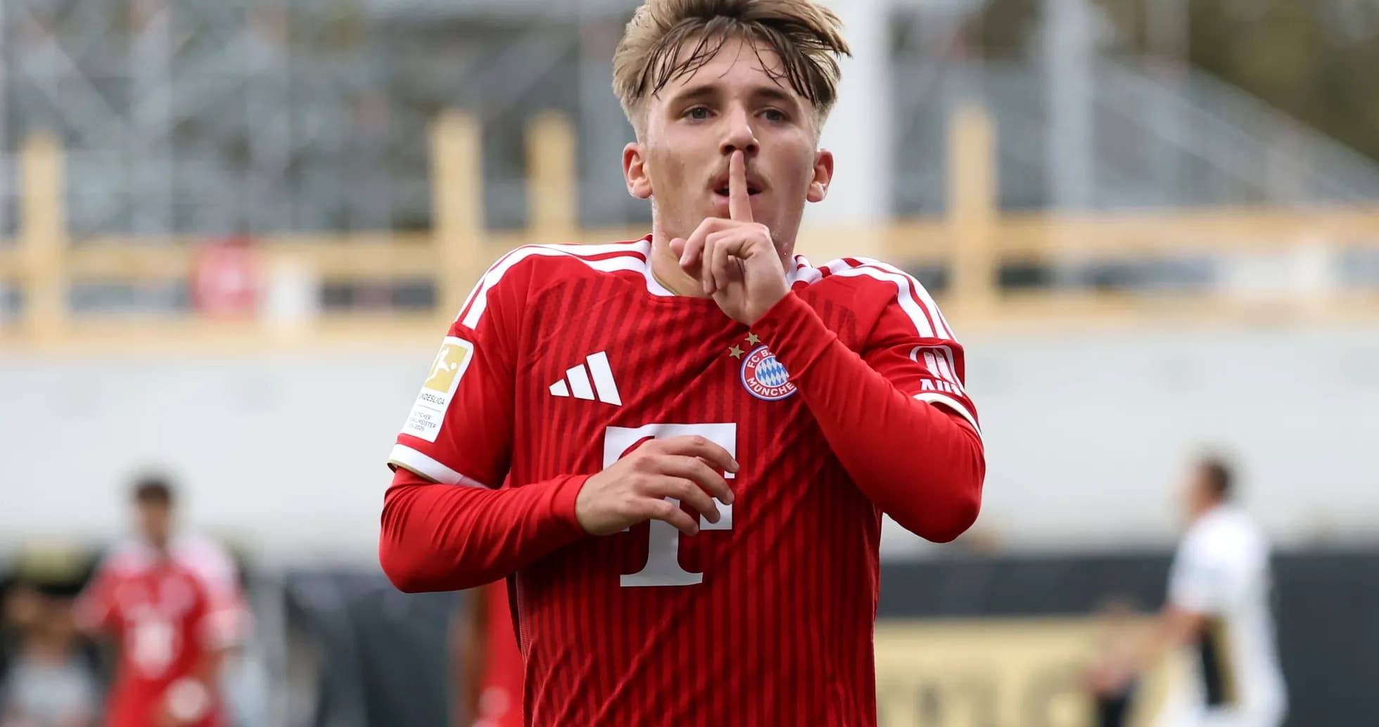 Player celebrating with a shushing gesture in red jersey