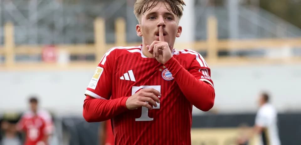 Player celebrating with a shushing gesture in red jersey