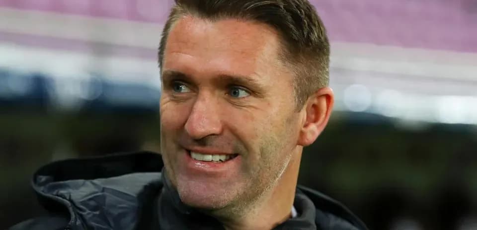 Coach smiling on the sidelines during a match