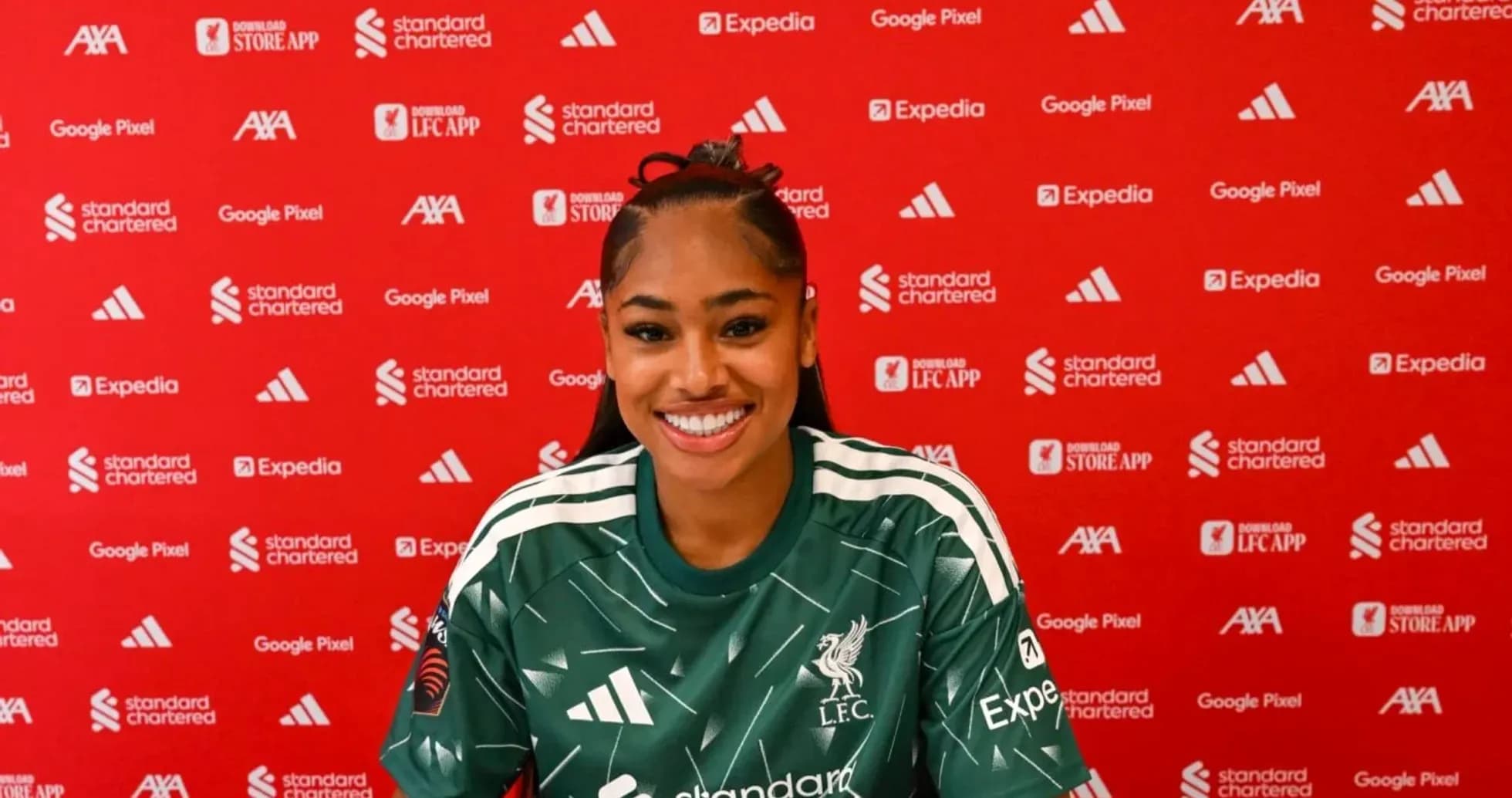 Player smiling during press conference with club backdrop