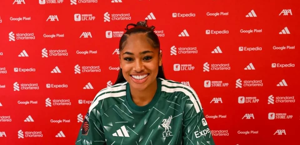 Player smiling during press conference with club backdrop