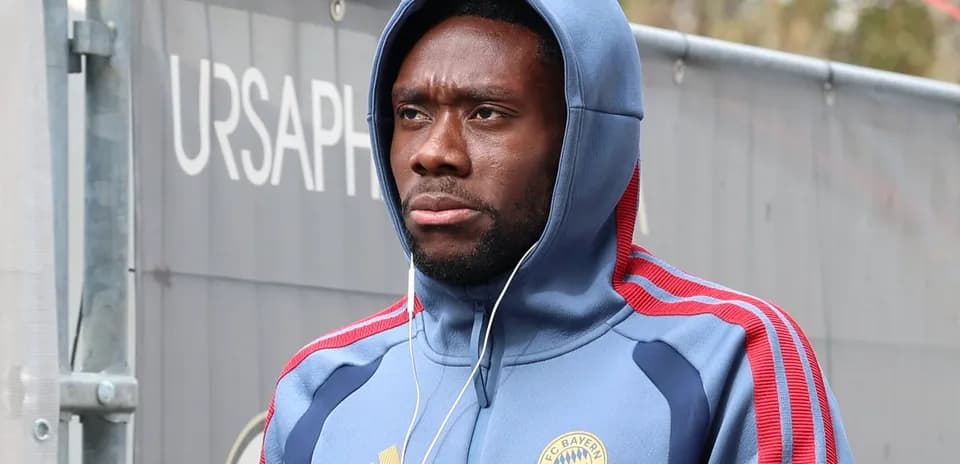 Player wearing Bayern Munich hoodie, walking with headphones