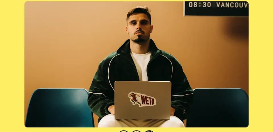 Man sitting with laptop displaying 'NETO' sticker