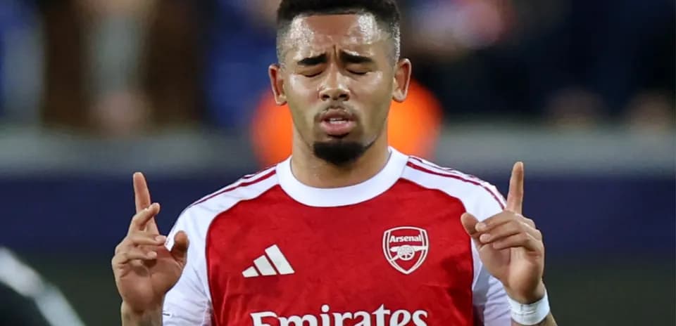 Player praying during a match wearing Arsenal jersey