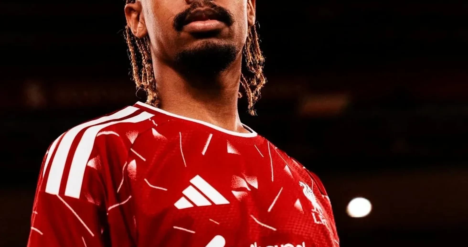 Player posing in red football kit with sponsor logo