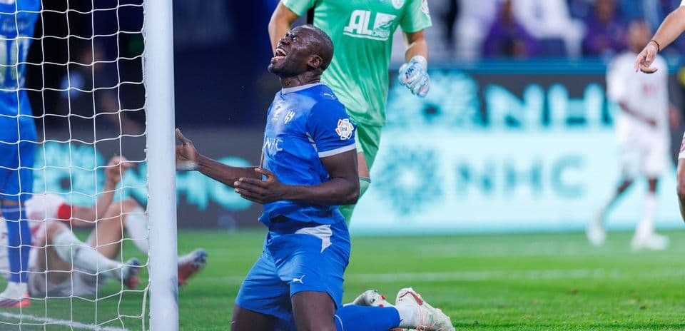 Player kneeling near goalpost after missed opportunity