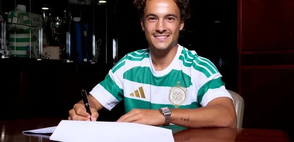 Player signing contract at desk wearing team jersey