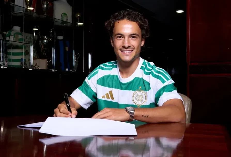 Player signing contract at desk wearing team jersey