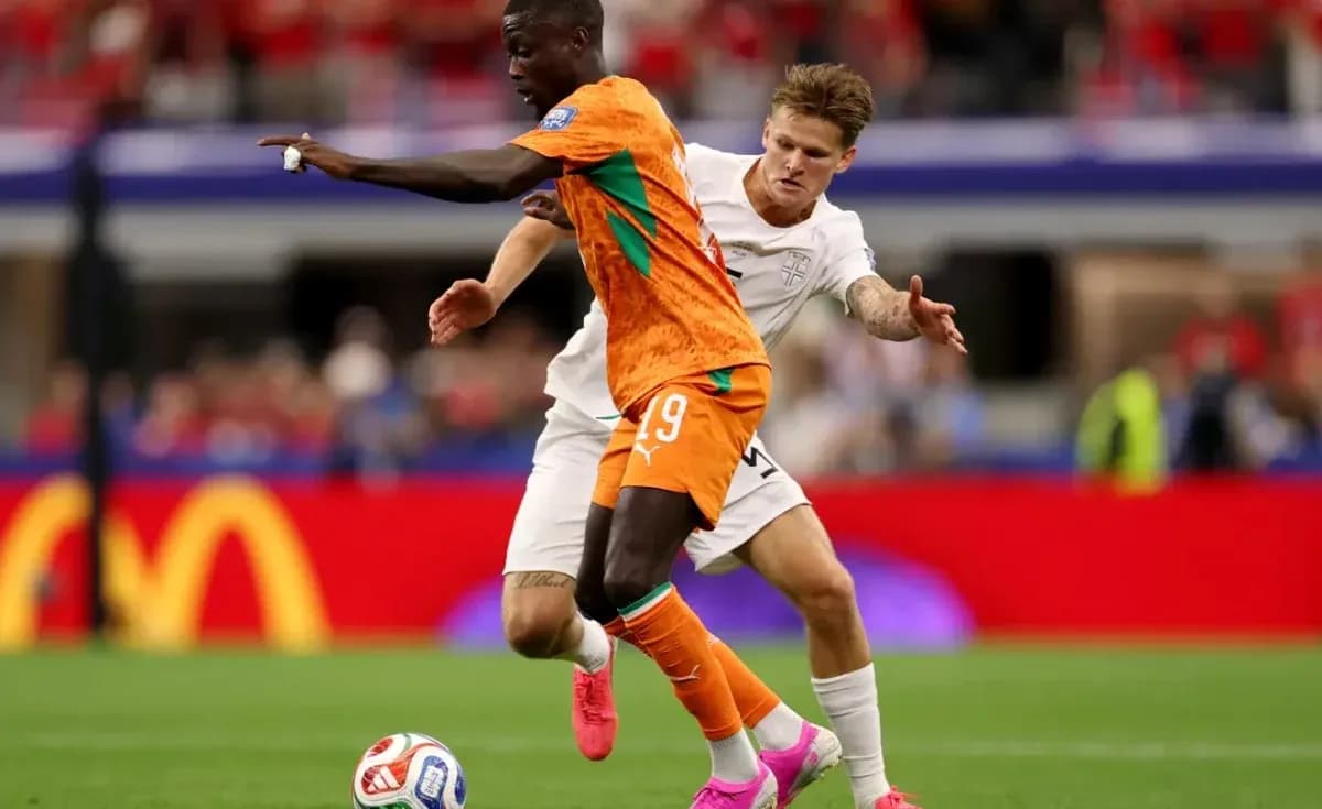 Player in orange jersey dribbling past opponent in white