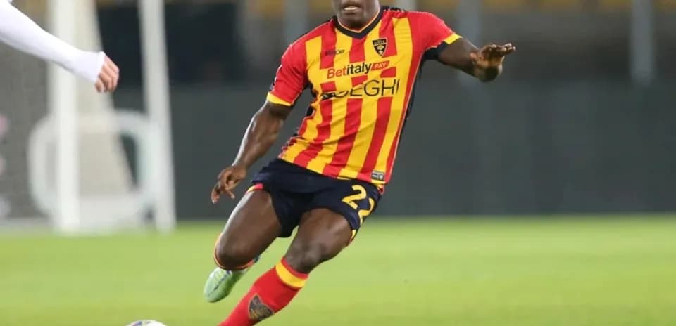 Player in red and yellow jersey dribbling ball