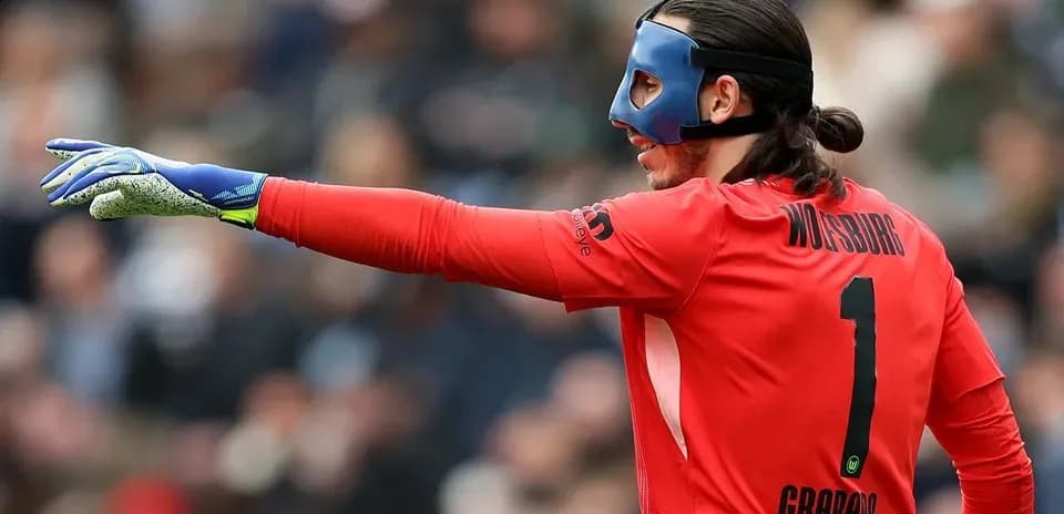 Goalkeeper in red kit directing play on field
