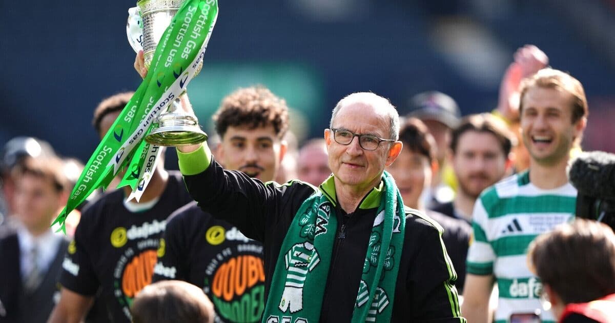 Coach holding trophy with team celebrating behind