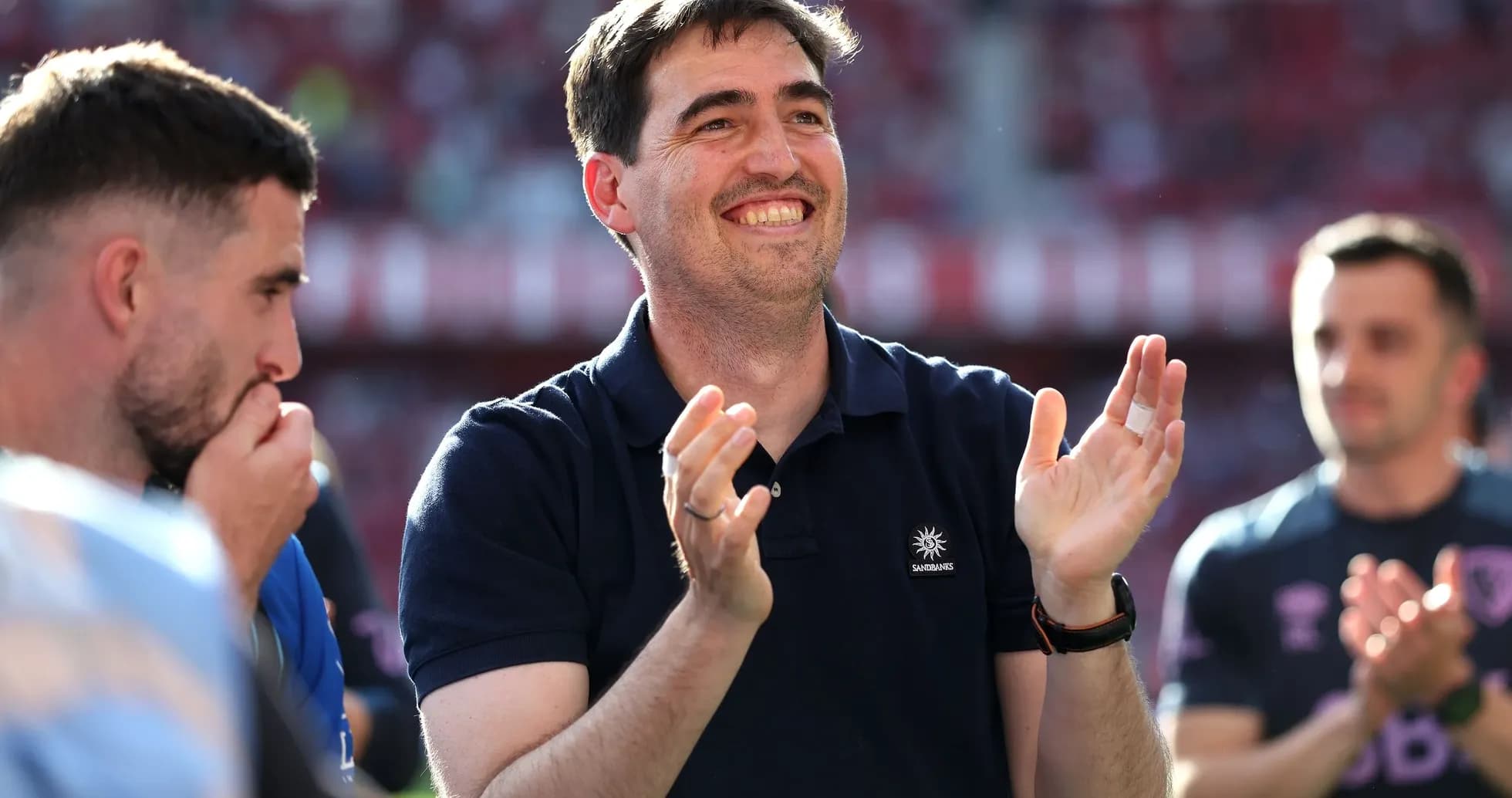 Coach applauding with players during post-match celebration