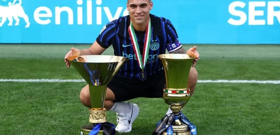 Player celebrating with two trophies on the field