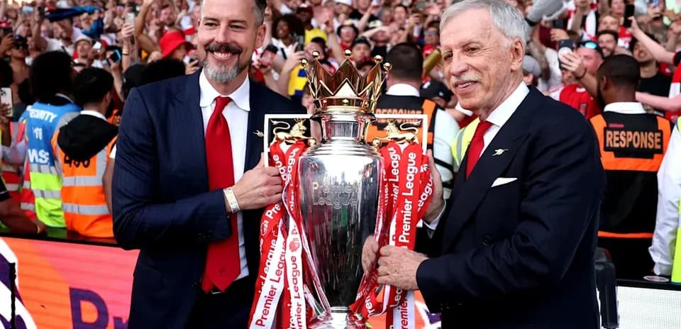 Two officials holding the Premier League trophy with fans