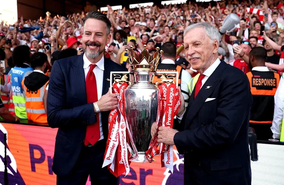Two officials holding the Premier League trophy with fans