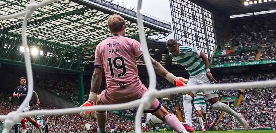 Celtic player attempting to score past goalkeeper Bain