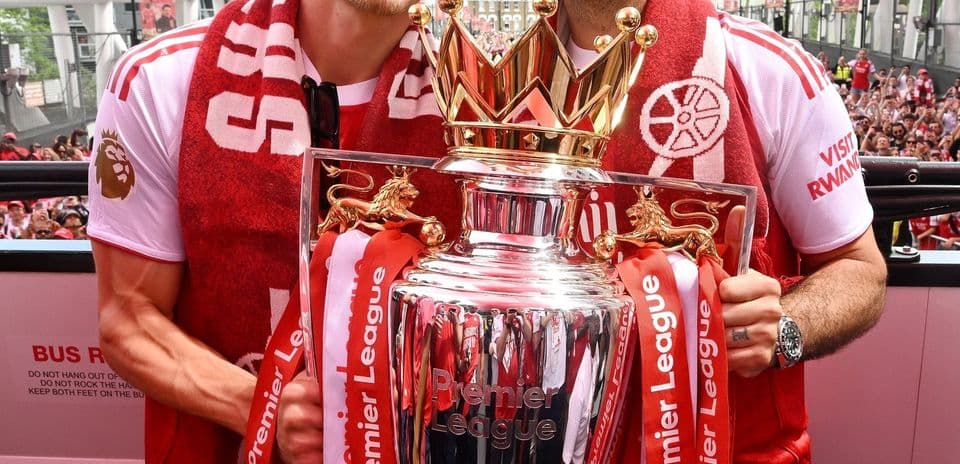 Players celebrating with Premier League trophy in crowd
