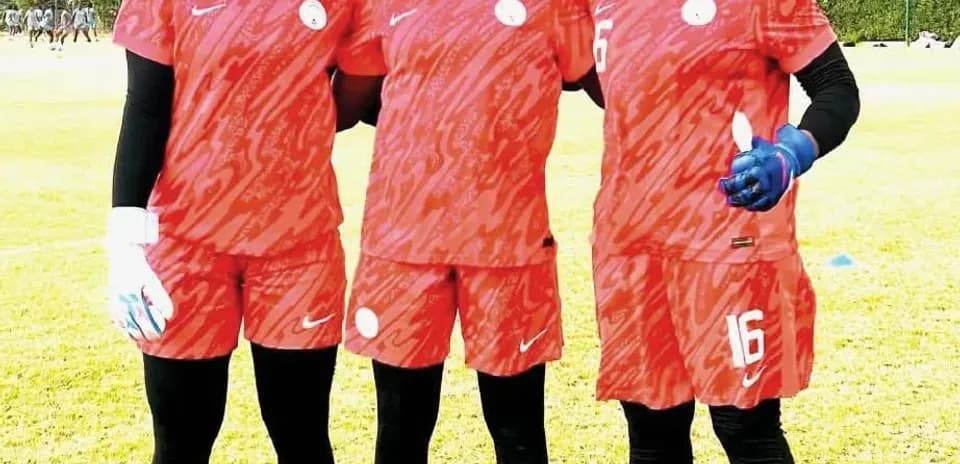 Three female football players in red uniforms posing together