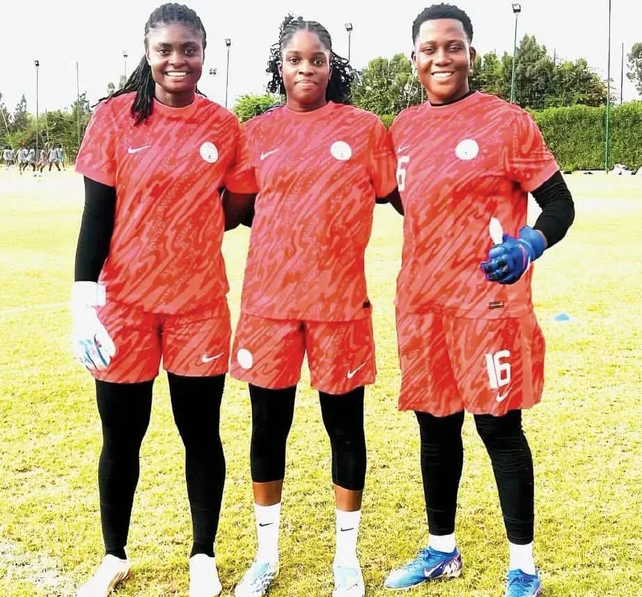 Three female football players in red uniforms posing together