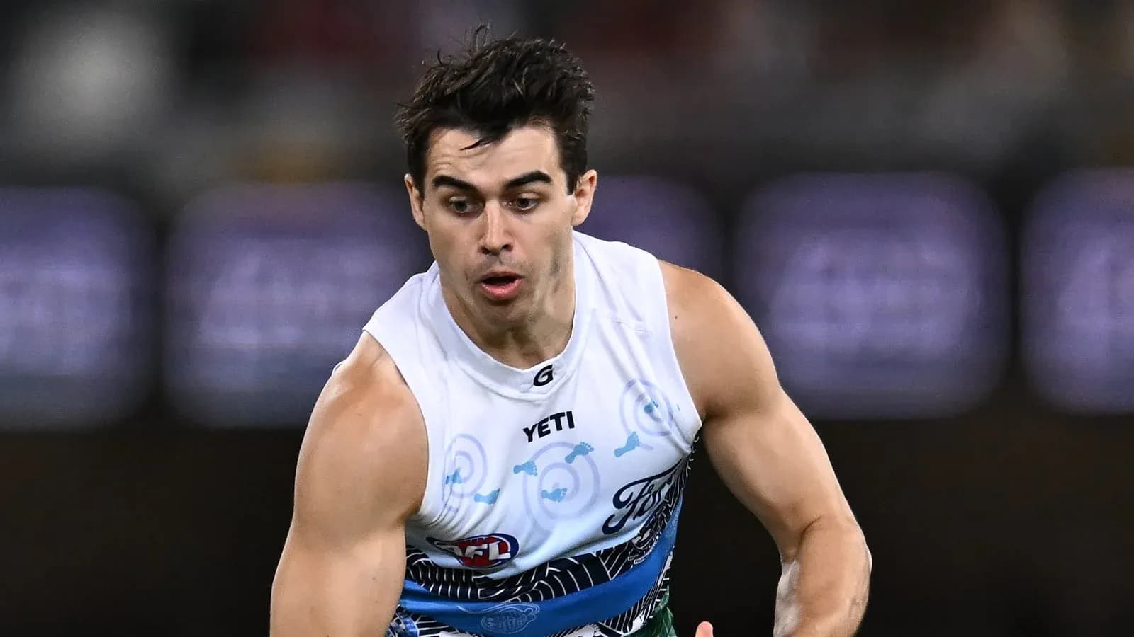 Player running with ball during AFL match